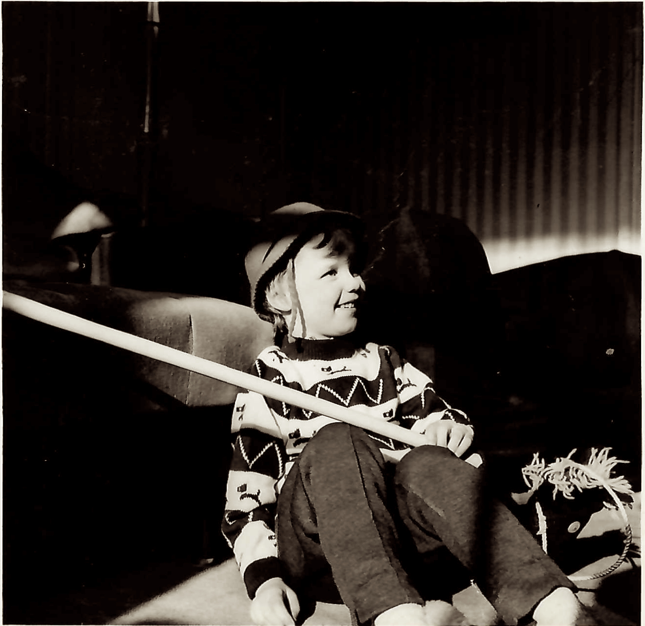 Black and white photo from early 1960s of a young child wearing a hat and holding a hand made 'hobby horse'