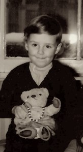 Black and white photo of a young child proudly holding a teddy bear