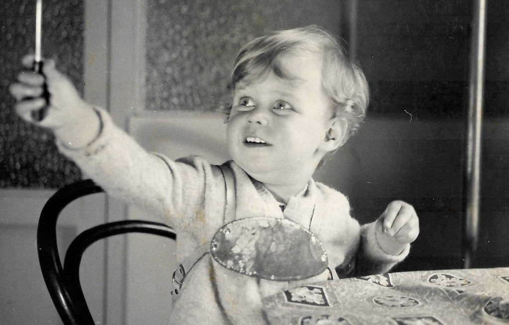 Black and white photo of small child c1960 playing with a screwdriver
