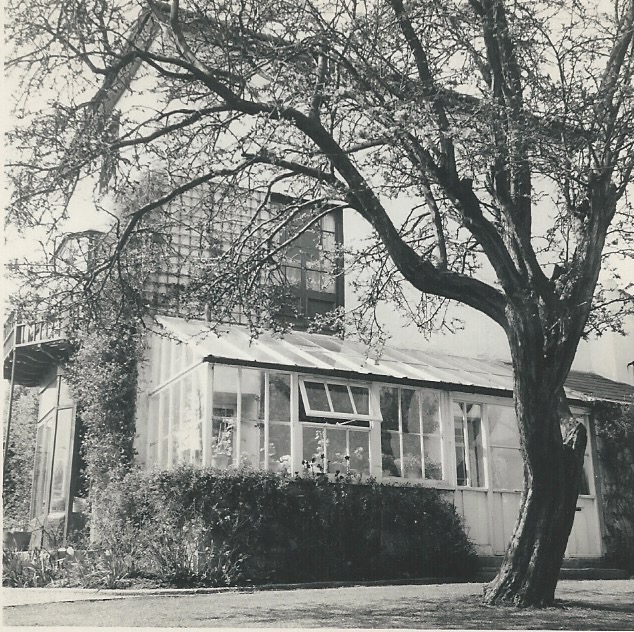 The front of a tall white Victorian House with a conservatory to the front and french windows with a balcony above