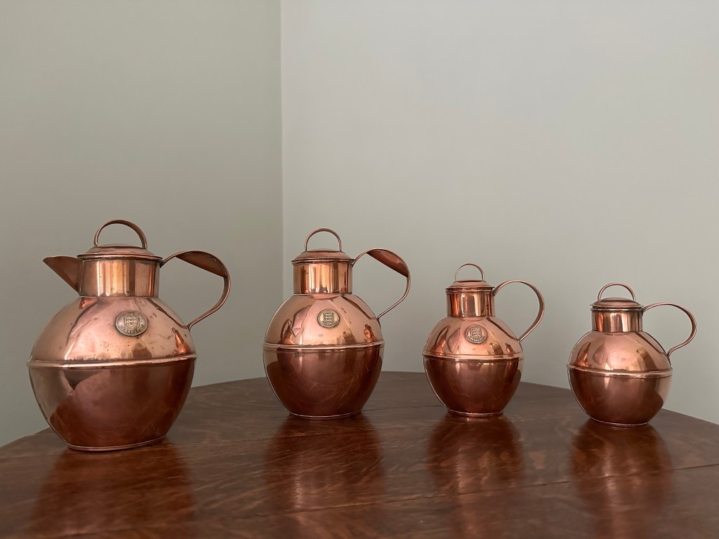 Four antique copper Guernsey milk cans that have been polished to a nice shiny rose finish