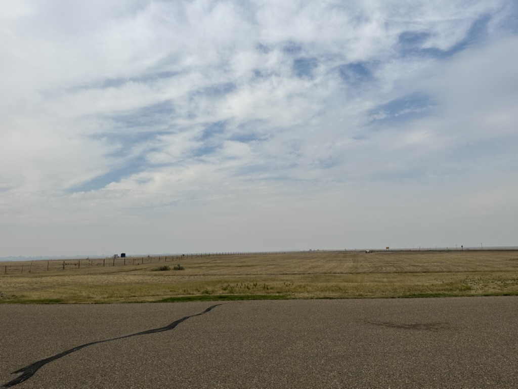 Looking west from the edge the Badlands, Alberta, Canada showing a road surface followed by flat dry prairie grassland beyond
