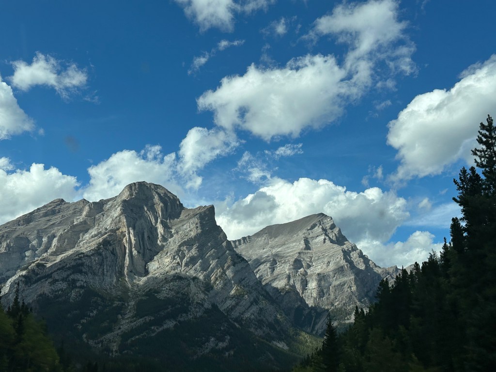 Craggy grey moutain peaks against a blue sky with some fluffy clouds