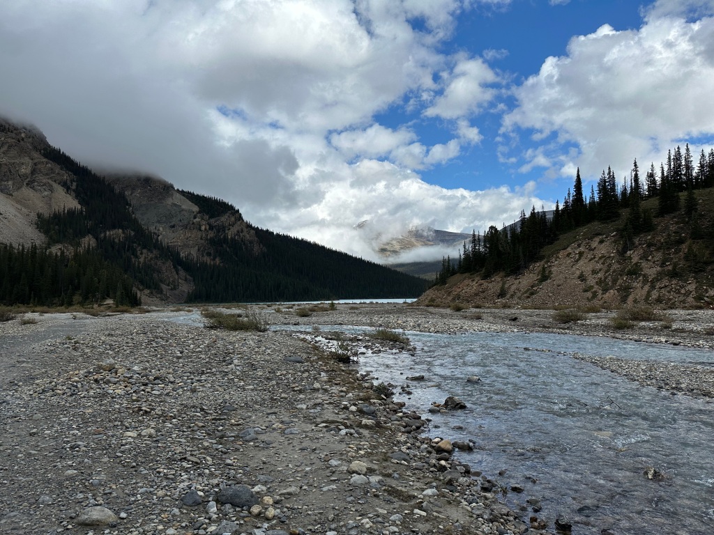 A clear mountain river flowing over stony ground with mountains in the background
