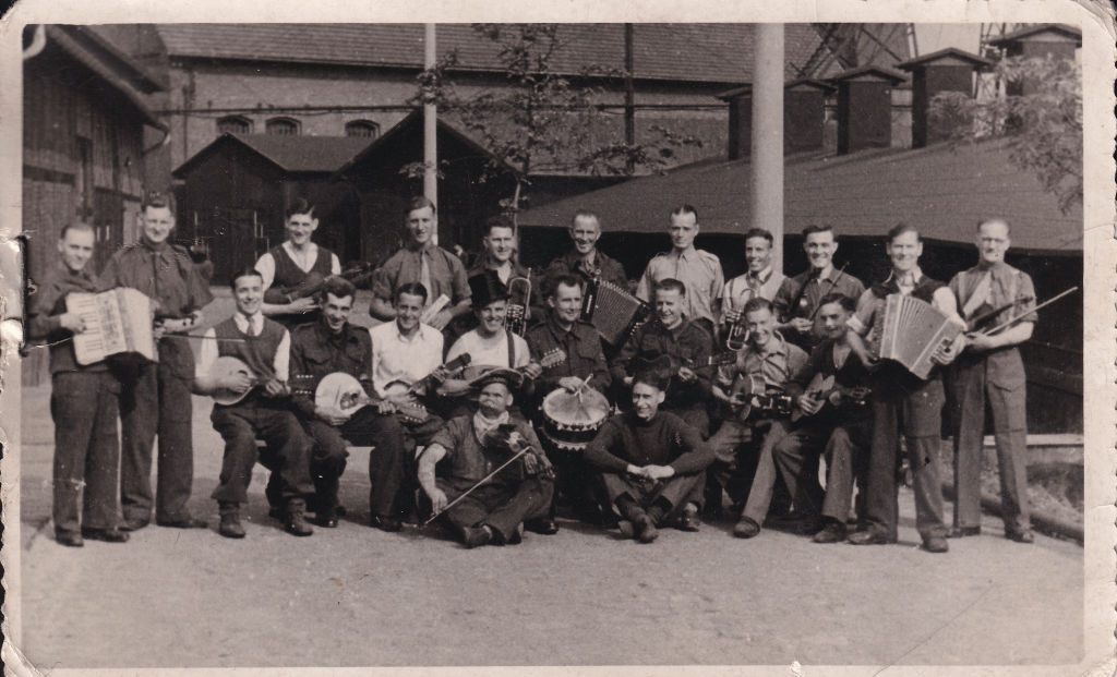 Group photo of 21 WW2 prisoners of war each holding a muscal instrument at E72 workcamp attached to Stalag VIIIB POW camp near Lamsdorf