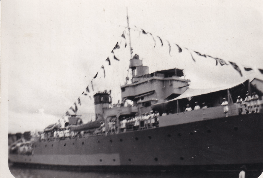 Black and white photograph of British minesweeper HMS Pickle during service in WW2. The ship is all dressed up with flags and members of the crew line the deck