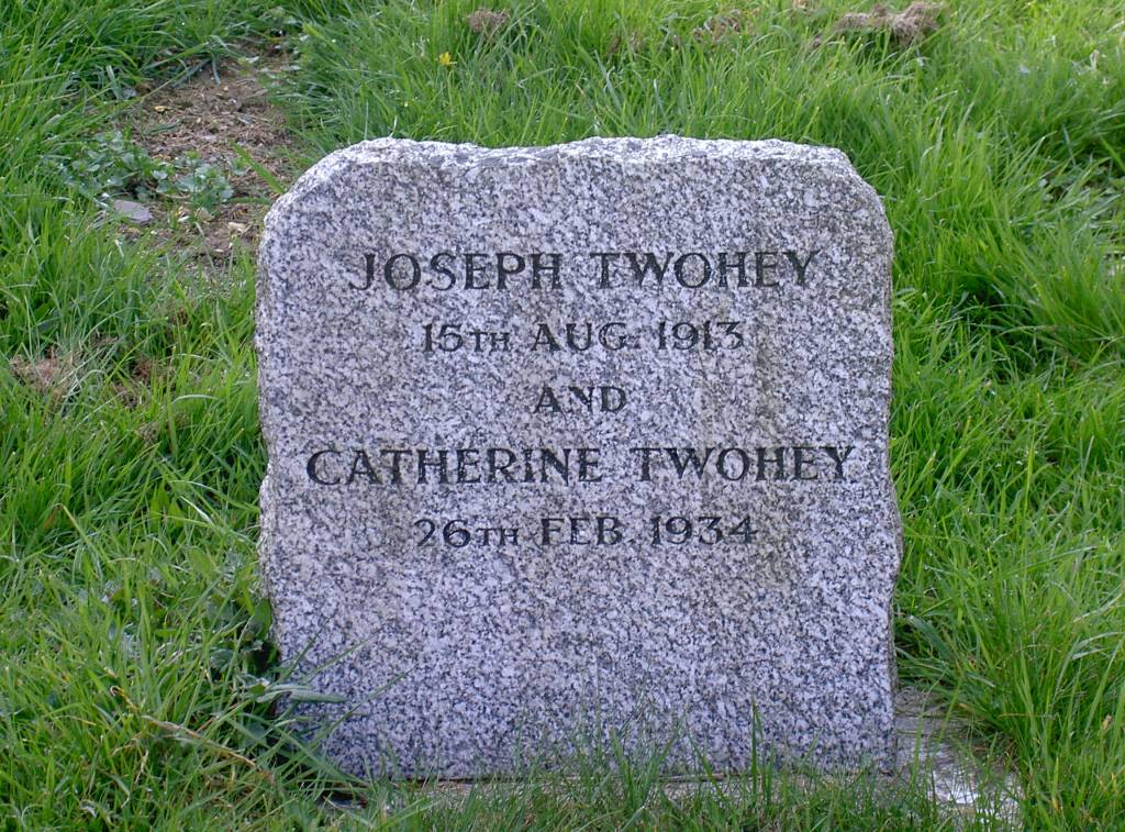 Gravestone of Joseph and Catherine Twohey, with their names and dates of death inscribed, surrounded by grass.