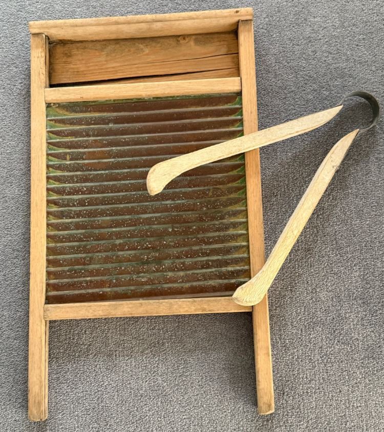 A traditional washboard made of wood and metal, featuring corrugated metal surface for scrubbing clothes, alongside two wooden gooseneck-shaped washing tools.