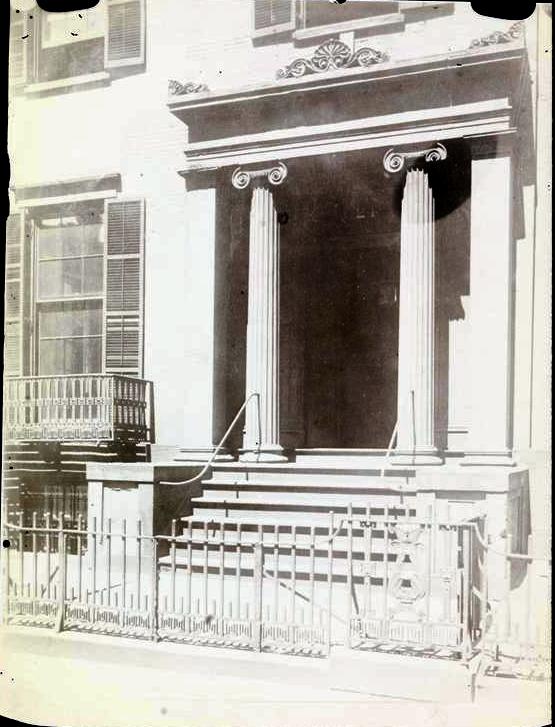 Entrance the Brevoort Mansion, a classical building with two large columns, steps leading to the door, and a decorative railing in front