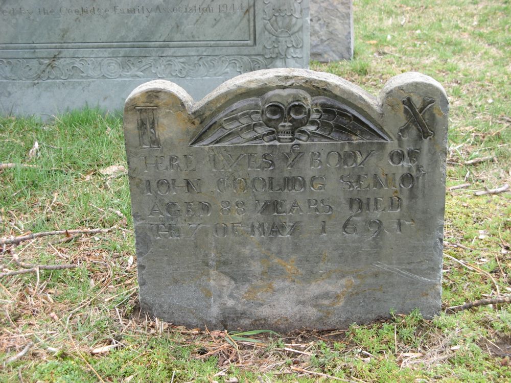 Gravestone John Coolidge Old gravestone with winged skull symbol and inscription reading Here lyes ye body of John Coolidge Senior, aged 88 years, died the 7 of May 1691
